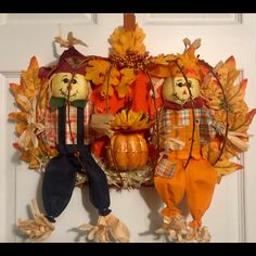 a couple of stuffed animals sitting on top of a door mat next to pumpkins