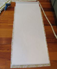 a piece of white paper sitting on top of a wooden floor next to a pair of scissors