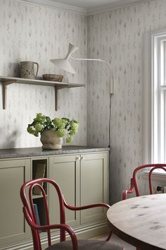 a table and chairs in a room next to a wallpapered wall with flowers