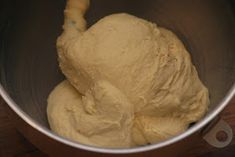 a metal bowl filled with dough on top of a wooden table