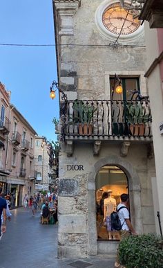 people are walking down the street in front of an old building with a clock on it