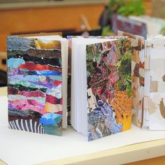 two open books sitting on top of a table next to each other with different colored papers