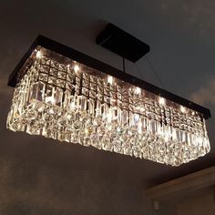 a crystal chandelier hanging from the ceiling in a room with dark walls and clouds