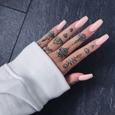 a woman's hand with tattoos on it and pink manicures in the middle