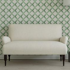 a white couch sitting in front of a green wall with diamond pattern on it's side