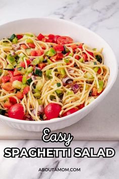 a white bowl filled with spaghetti salad on top of a marble counter next to a knife and fork