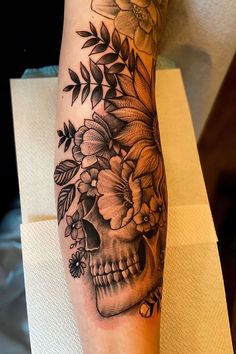 a woman's leg with a skull and flowers on it