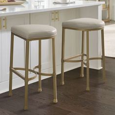 two beige stools sitting in front of a white counter top next to an island