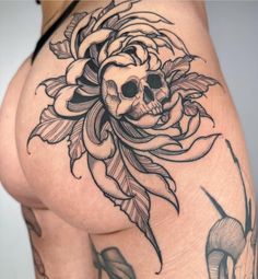 a woman's thigh with a skull and rose tattoo on it