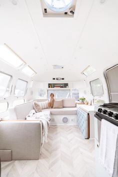 a woman sitting on a couch in the back of a camper