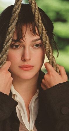 a woman is holding up two ropes on her head and looking at the camera while wearing a black jacket