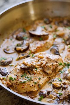 a pan filled with chicken and mushrooms on top of a table