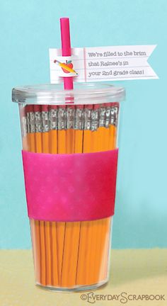 a cup filled with orange and pink colored pencils