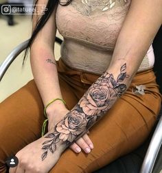 a woman sitting in a chair with a tattoo on her arm and wrist, holding onto the