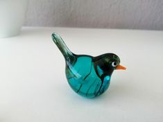 a glass bird sitting on top of a white table