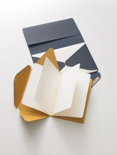 an open book sitting on top of a table next to other papers and envelopes