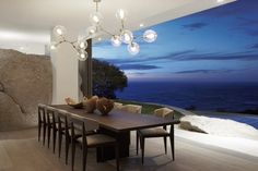 a dining room with a table and chairs in front of a large window overlooking the ocean