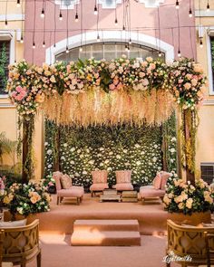 an outdoor ceremony setup with flowers and greenery on the wall, couches and chairs