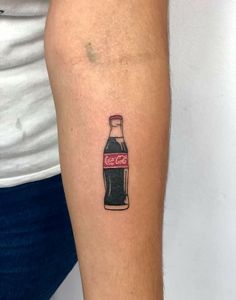 a person with a tattoo on their arm has a coca - cola bottle in it