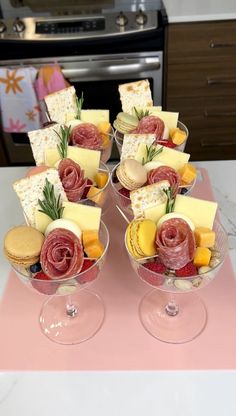 two wine glasses filled with different types of cheese and crackers on top of a table