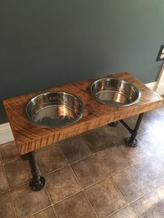 two stainless steel bowls are sitting on a wooden table in the corner of a room