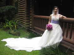 a woman in a wedding dress posing for a photo on the deck of a log cabin