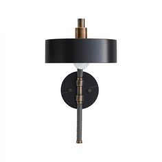 a black and gold wall light with a round shade on the top, attached to a metal rod