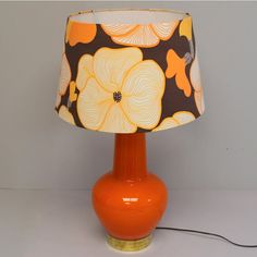 an orange table lamp with a black and yellow flower print lampshade on it