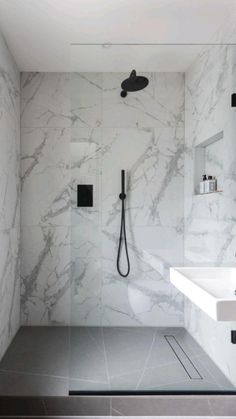 a bathroom with marble walls and flooring, black faucet on the shower head