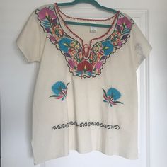 Never Worn- Authentic Embroidered Mexican Blouse. Made And Purchased In Mexico. Multicolored Embroidery Along The Front Neckline And At The Bottom. There Is A Dye Stain On The Left Sleeve That Came With The Blouse When I Got It. White V-neck Top With Intricate Embroidery, White Folk Style V-neck Blouse, White Crew Neck Blouse With Floral Embroidery, White Embroidered Crew Neck Blouse, Traditional V-neck Top With Geometric Embroidery, Folk Style White V-neck Blouse, Red Short Sleeve Top With Embroidered Hem, Traditional V-neck Top With Floral Embroidery, Traditional White V-neck Embroidered Top