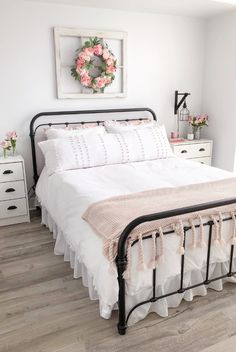 a bedroom with white bedding and pink flowers on the wall above the headboard