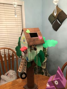 a house made out of cardboard sitting on top of a table next to a tree