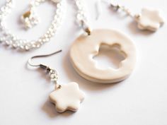 a white necklace and earring sitting next to each other on top of a table