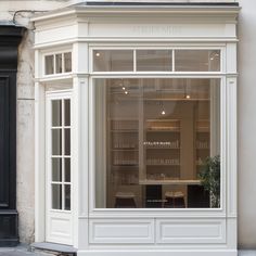 a store front with an open window on the side of it and a potted plant inside