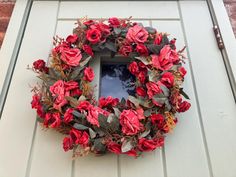 a wreath with red flowers is hanging on the door