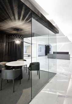 an office with large glass walls and white flooring on the wall is furnished with modern furniture