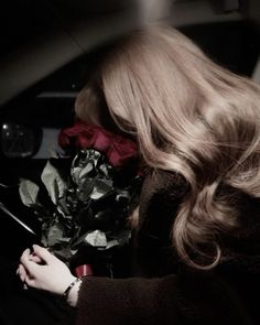 a woman holding a bouquet of flowers in her hand and looking down at the ground