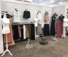 a clothing store with mannequins and dresses on display in front of white brick walls