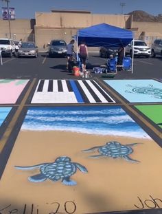 some people are standing in the parking lot with paintings on the ground and under tents