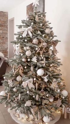 a decorated christmas tree in a living room with white and silver ornaments on the top