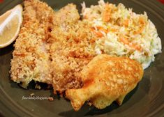 a green plate topped with fried fish and coleslaw next to a lemon wedge