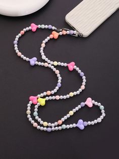 a necklace with pastel hearts on it next to a cell phone and wallet case