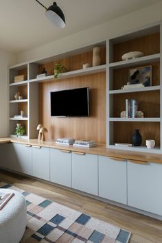 a living room filled with furniture and a flat screen tv mounted on a wall above it