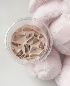 a pink stuffed animal next to a plastic cup with liquid in it's mouth