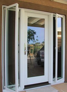 an open white door on the outside of a building with glass doors and sidelights