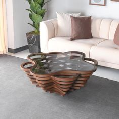 a living room with a couch, table and potted plant on the floor in front of it