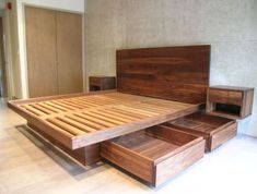 a wooden bed with two drawers on each side and an open drawer in the middle