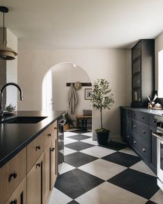 a black and white checkered kitchen floor with an arched doorway leading into the dining room