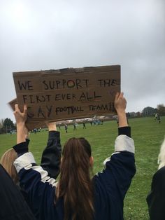 two people holding up a sign that says we support the first ever all gay football team