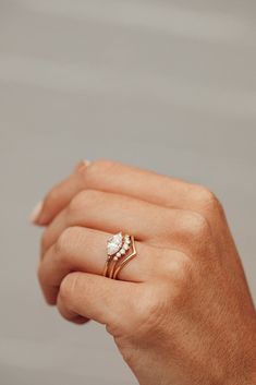 a woman's hand holding an engagement ring with two diamonds on it and the other hand